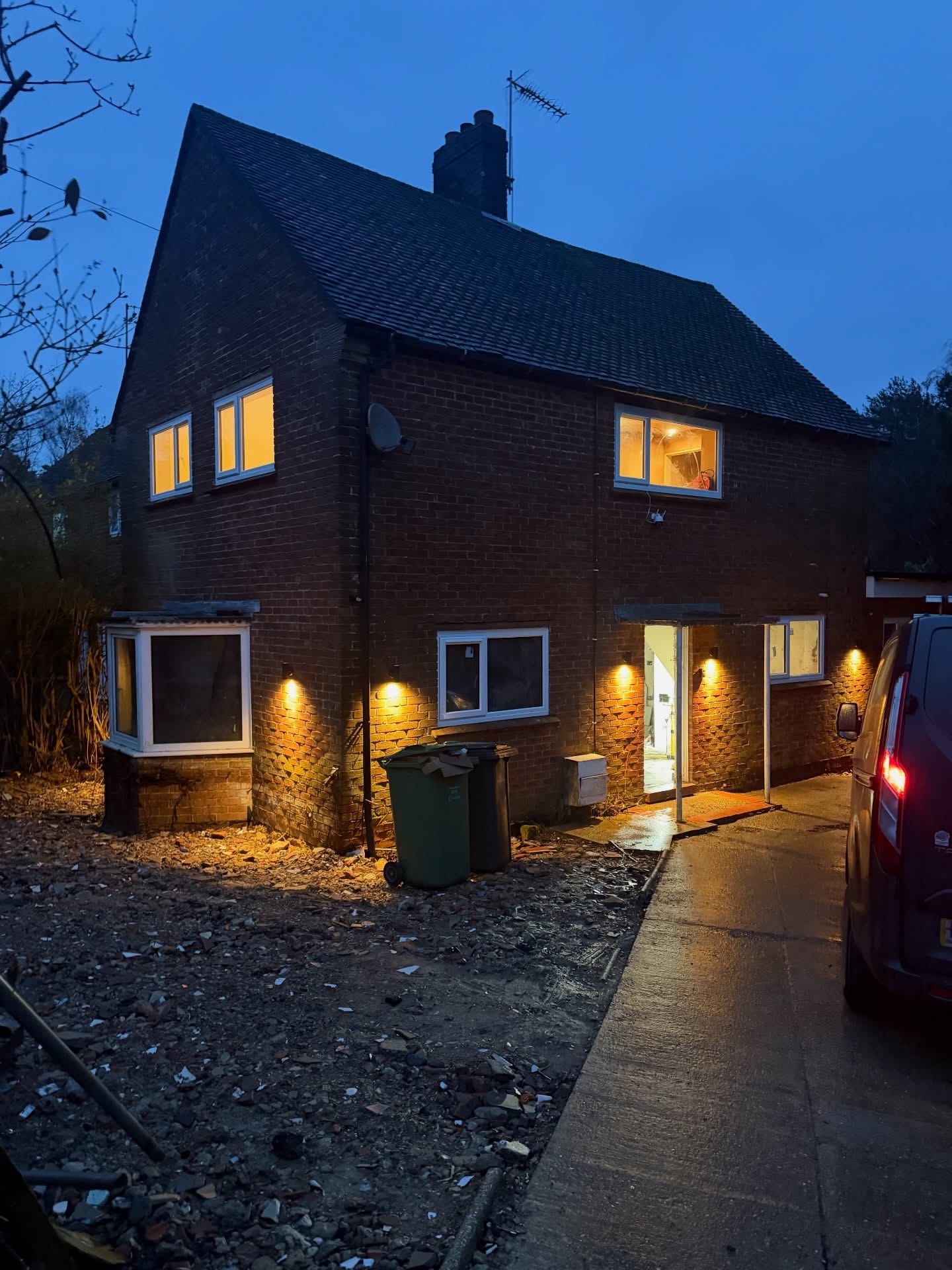 Brick house at dusk with black exterior wall lights casting warm light down the front elevation
